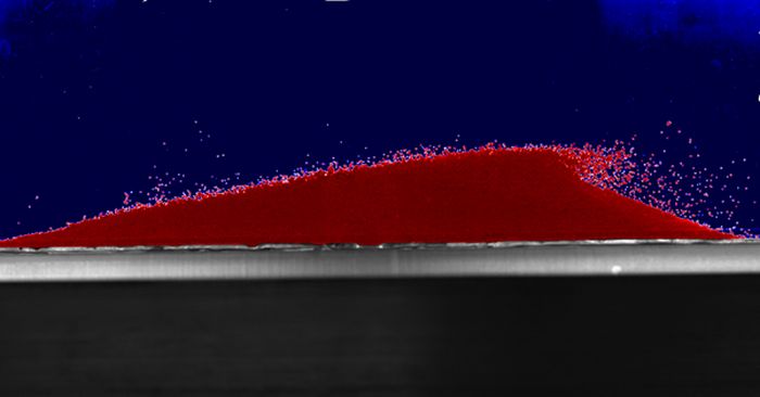 Imagen de dunas de arena del experimento realizado con bolas de cristal.  Se puede ver cómo el movimiento del agua los empuja repentinamente hacia arriba por la ladera de sotavento de la duna.  Fuente: Carol Pasek, Natalie Friend