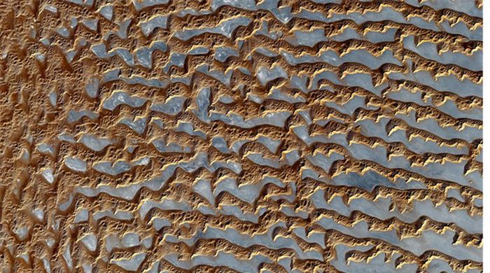 En la empresa se encuentran a menudo dunas de arena.  El Dr. Karl Pasek estudió las interacciones entre estas crestas de arena.  Dunas de arena en el Barrio Vacío, Península Arábiga.  Imagen de NASA/GSFC/METI/ERSDAC/JAROS y el equipo científico ASTER de EE. UU. y Japón 
