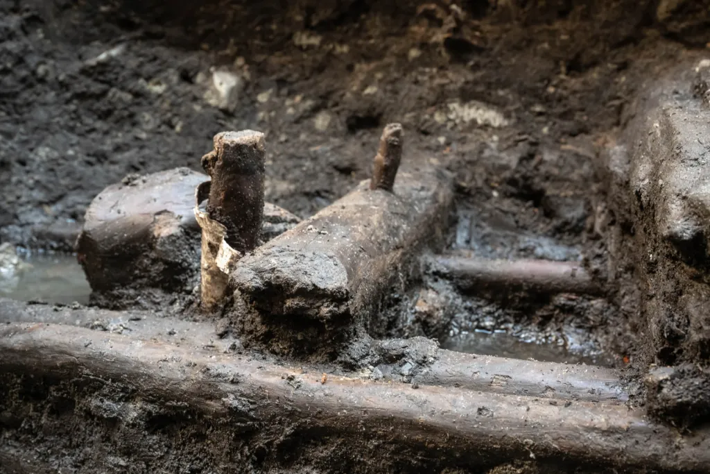 Toruń, 19.11.2025. Fragment nieznanych wcześniej drewnianych konstrukcji z XIII wieku, 19 bm. w Toruniu. Konstrukcje odkryte zostały podczas badań archelogocznych na dziedzińcu Domu Mikołaja Kopernika w Toruniu. To jedne z najstarszych takich znalezisk w mieście. Konstrukcje trafią do konserwacji i staną się elementem przyszłej wystawy stałej muzeum. (mr) PAP/Tytus Żmijewski