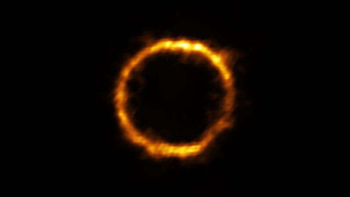 Galaktyka SPT0418-47 zaobserwowana przy pomocy sieci radioteleskopów ALMA. Odległa jest od nas o 12 mld lat świetlnych. Widoczny pierścień to efekt soczewkowania grawitacyjnego. Źródło: ALMA (ESO/NAOJ/NRAO), Rizzo et al.   