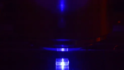 Kryształ fluorku litu z zarejestrowanymi śladami ciężkich jonów podczas  oglądania pod mikroskopem fluorescencyjnym. (Źródło: IFJ PAN)