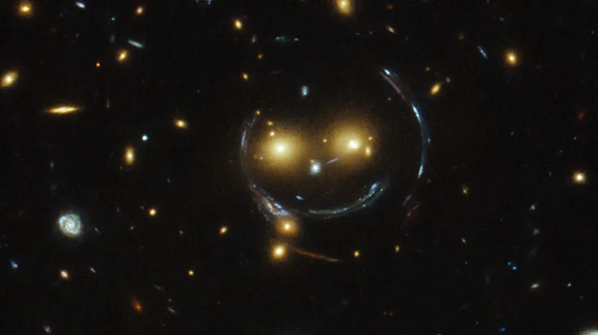 Gromada galaktyk SDSS J1038+4849 działająca jako soczewka grawitacyjna i widoczny wokół niej pierścień Einsteina (łuki zniekształconych obrazów dalszych galaktyk). Źródło: NASA & ESA.