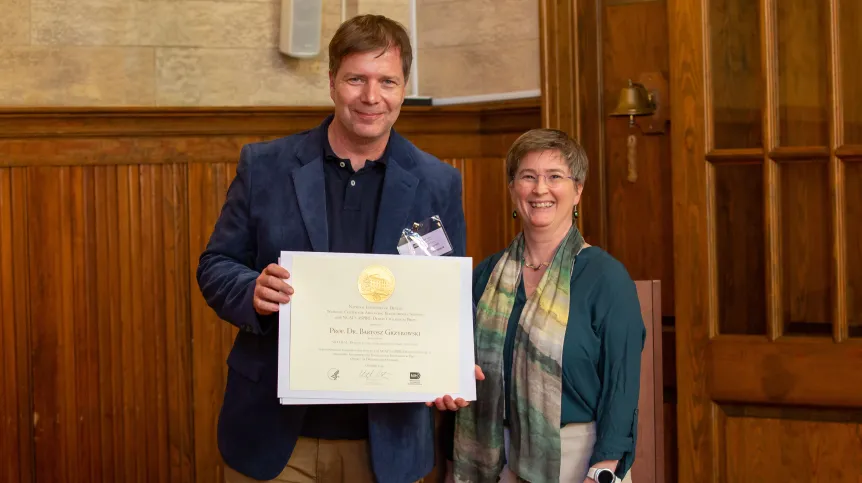 Profesor Bartosz Grzybowski odbierający w Waszyngtonie, w siedzibie Narodowego Instytutu Zdrowia (NIH) nagrodę ASPIRE za badania nad komputerowym planowaniem nieuzależniających leków przeciwbólowych (październik 2019).