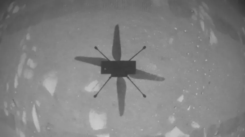 Fotografia wykonana przez drona Ingenuity w trakcie pierwszego lotu na Marsie. Widać cień rzucany przez drona. Źródło: NASA/JPL-Caltech