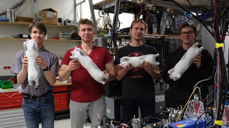 Źródło: Uniwersytet Warszawski. Studenci w laboratorium prezentujący obrót kotów Schrödingera (fot.: S. Kurzyna oraz B. Niewelt)