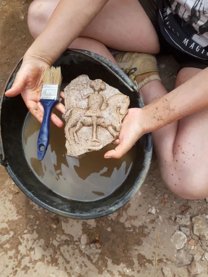 W jednej ze szczelin archeolodzy odkryli średniowieczny kafel piecowy, fot. M. Urbanowski